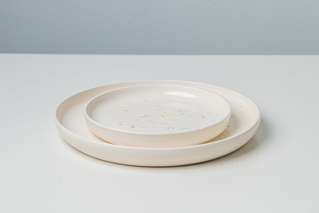 Large and small pottery plates. White with colored spakles.