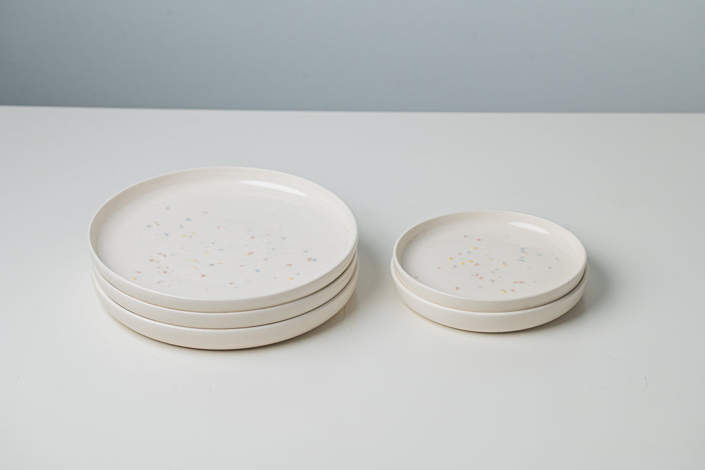 Grandes et petites assiettes en céramique artisanale. Blanches avec confettis de couleur.
