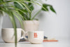Samll promotional coffee mug, white with colored logo. Made in Canada.